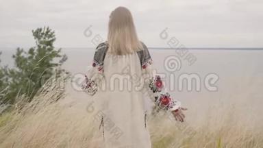 后景为敬畏的白种人女人，穿着夏日的长时装，站在湖边或湖边的田野上